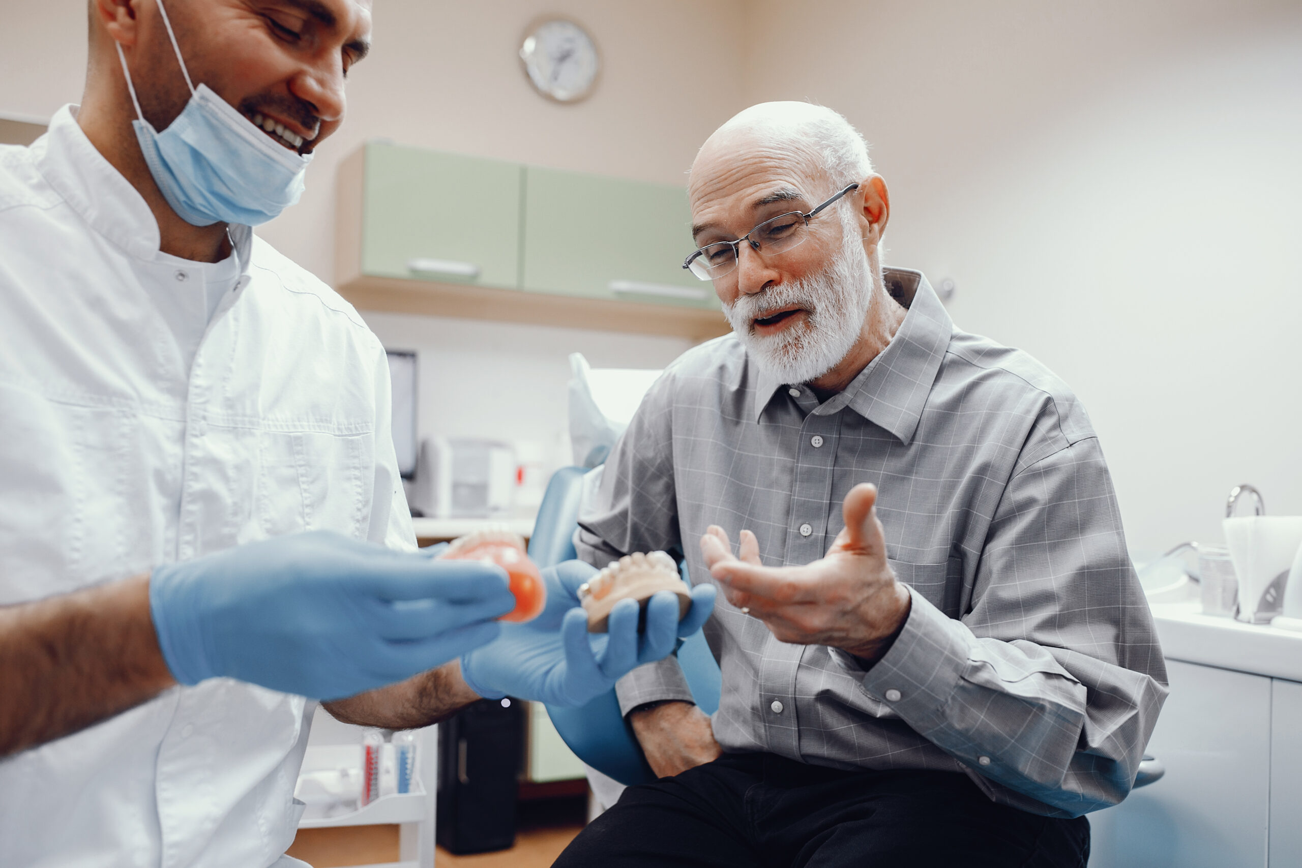 Old man sitting in the dentist's office Handsome old man talking to the dendist. Two men in the dentist's office. The doctor shows the patient dentures